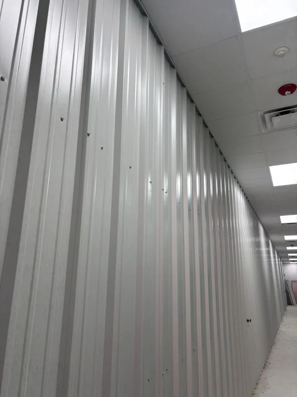 Ribbed Insulated Metal Panel (IMP) walls along an interior corridor